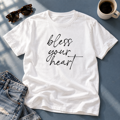 White Bless Your Heart tee with jeans, sunglasses, and coffee on a blue-gray surface.