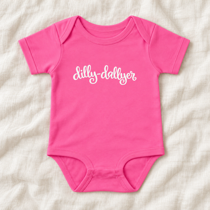 Hot Pink baby bodysuit with white “dilly-dallyer” script, laid flat on ivory linen