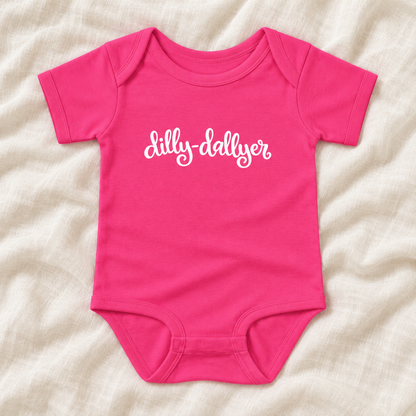 Raspberry baby bodysuit with white “dilly-dallyer” script, laid flat on ivory linen