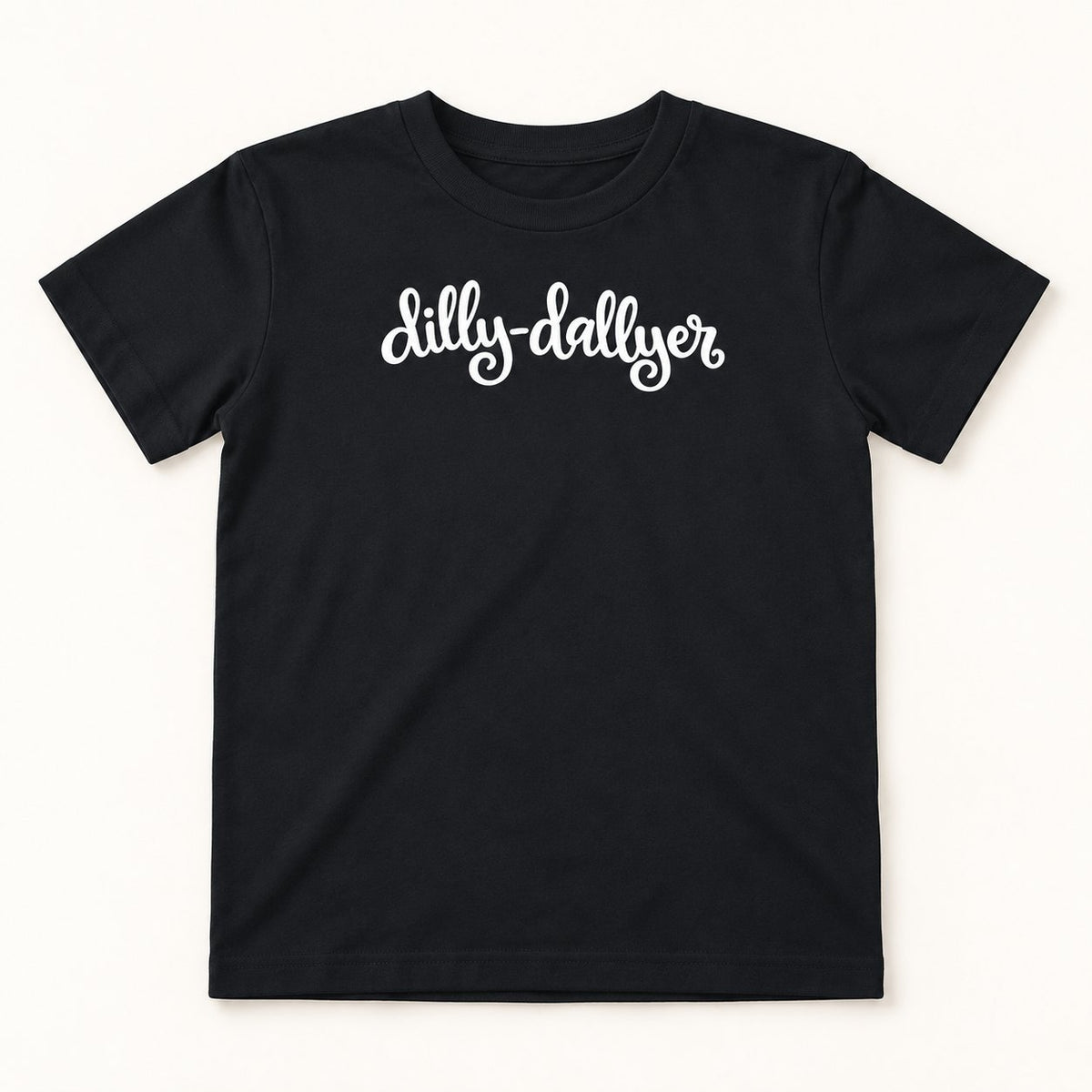 Black Dilly-Dallyer kids tee with white script, flat on a cream background