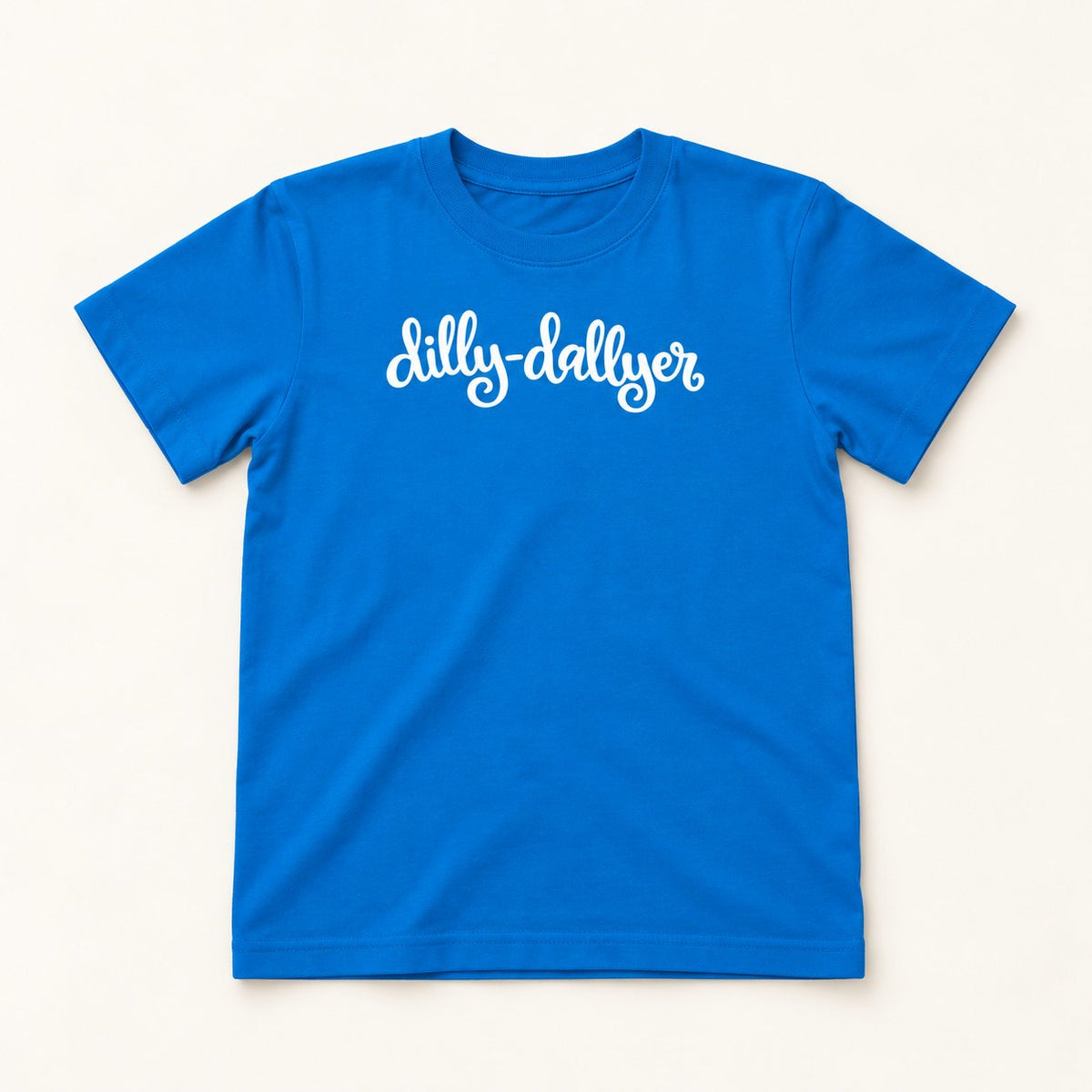 Cobalt Dilly-Dallyer kids tee with white script, flat on a cream background