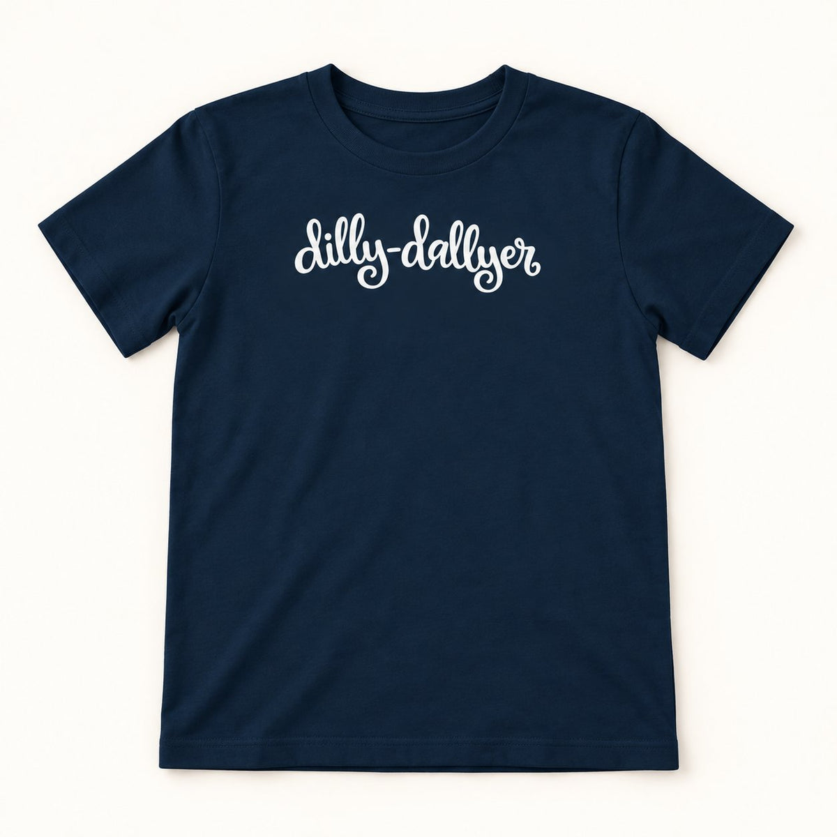 Navy Dilly-Dallyer kids tee with white script, flat on a cream background