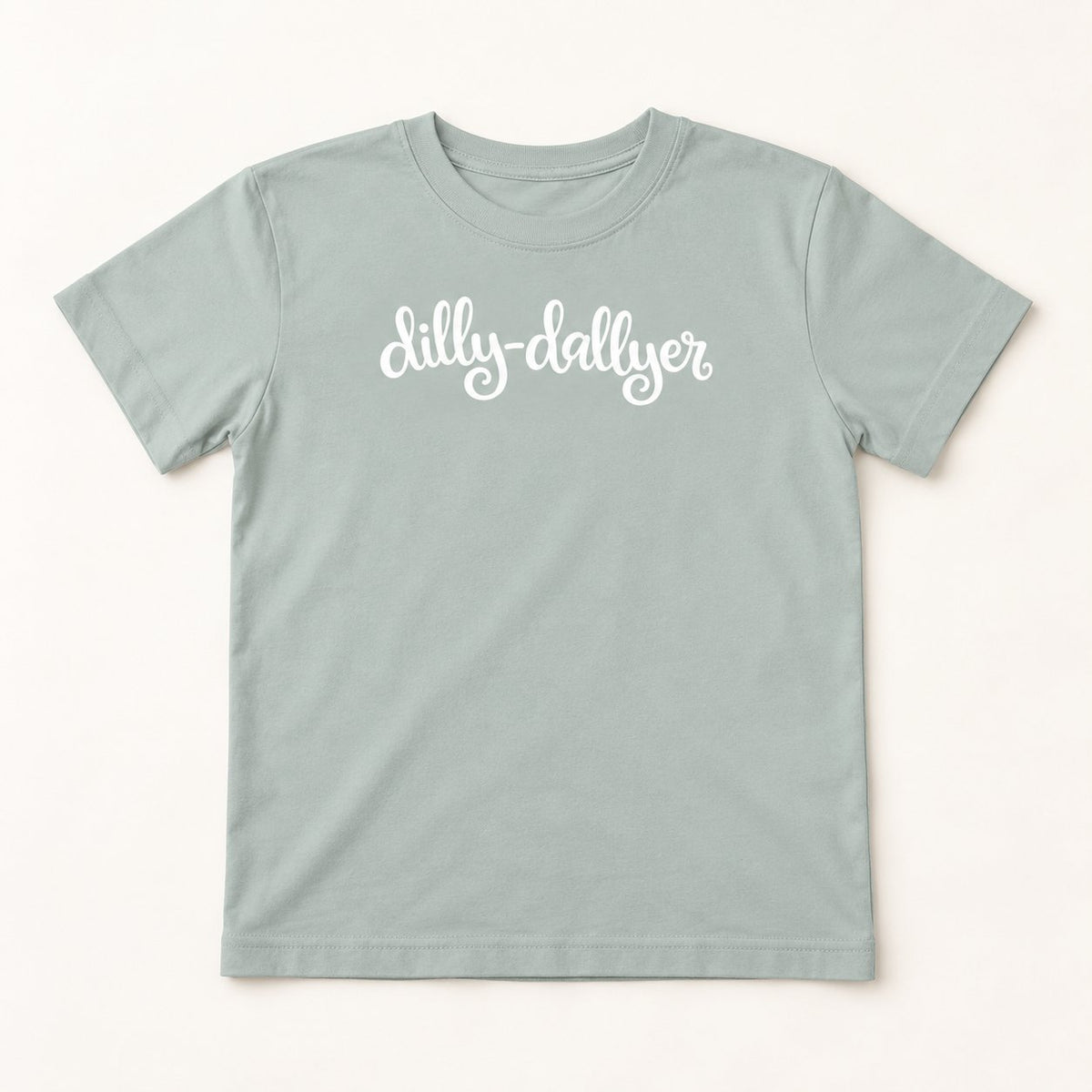 Silver Dilly-Dallyer kids tee with white script, flat on a cream background