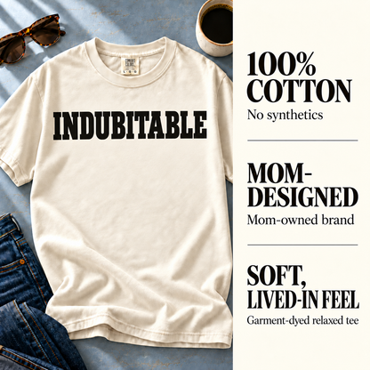 Ivory Indubitable tee beside 100% cotton, mom-owned brand, and garment-dyed fabric details.