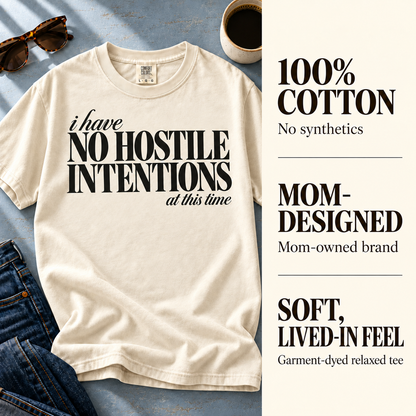 Ivory I Have No Hostile Intentions tee beside 100% cotton, mom-owned brand, and garment-dyed fabric details.