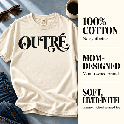 Ivory Outré tee with callouts for 100% cotton, mom-owned design, and garment-dyed fabric.